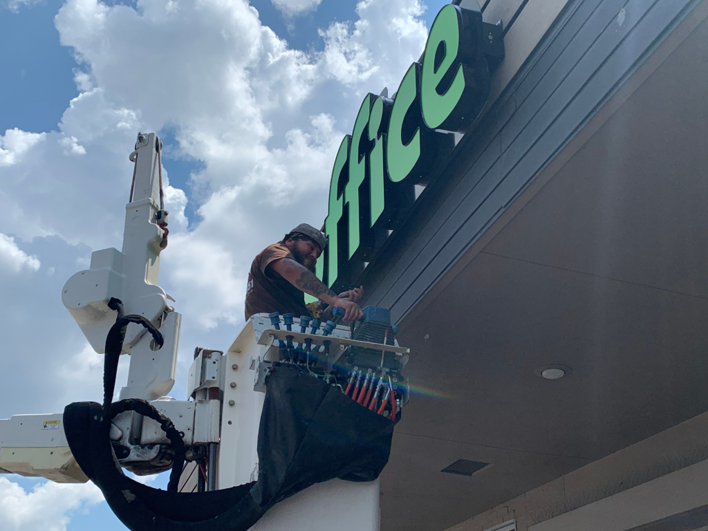 It's A Good Sign team installing front store sign